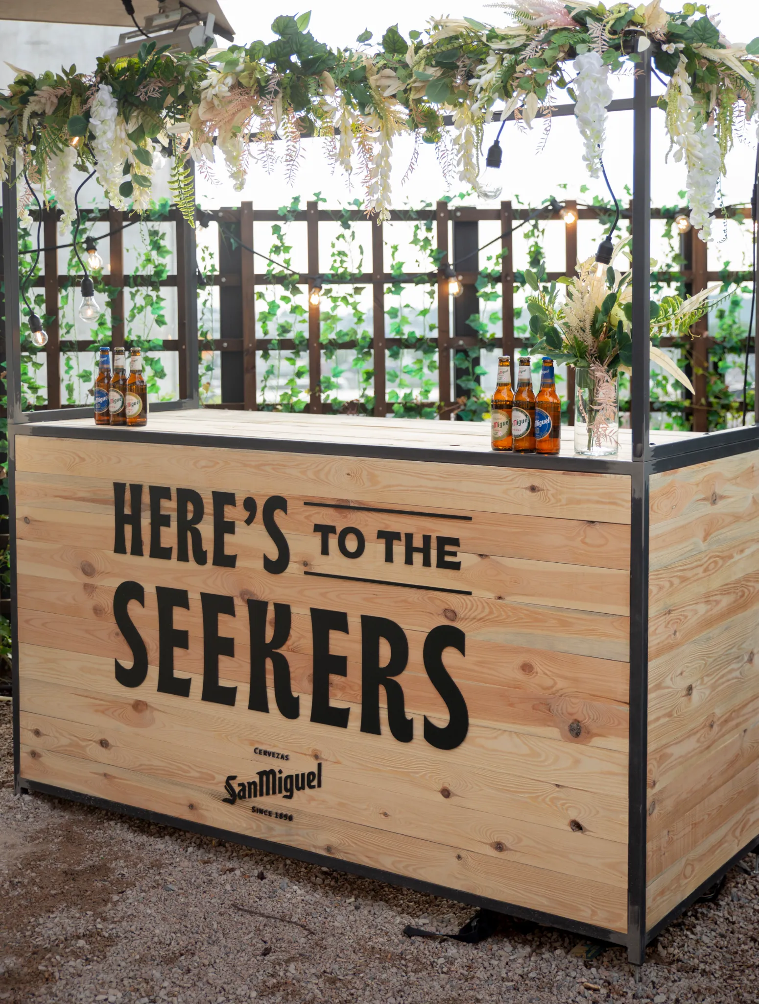 San Miguel branded bar stand decorated with flowers and beer bottles.